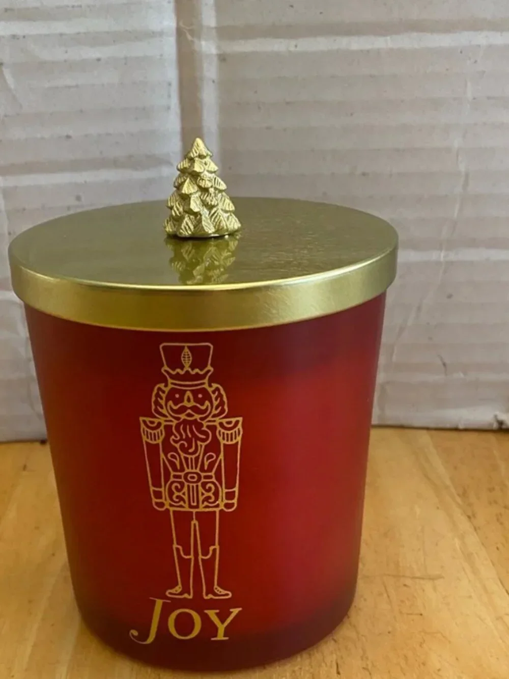 Holiday scented cranberry Candle with Nutcracker Design and gold tree topper.NWT